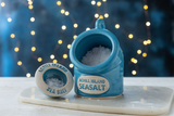 Blue ceramic sea salt pig and pinch pot set with 'Achill Island Seasalt' label on a blurred lights background