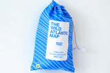 Blue drawstring bag with 'The Wild Atlantic Map' beach towel on a white background