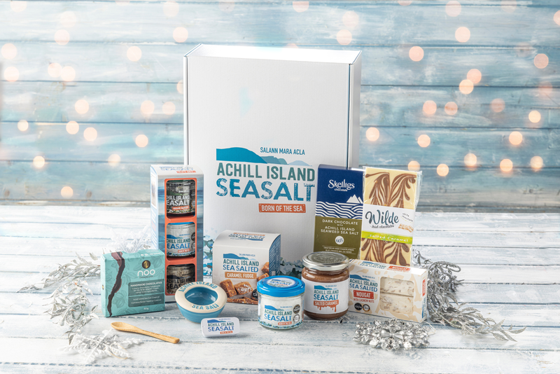 Collection of Achill Island Sea Salt products on a wooden surface with a festive background.