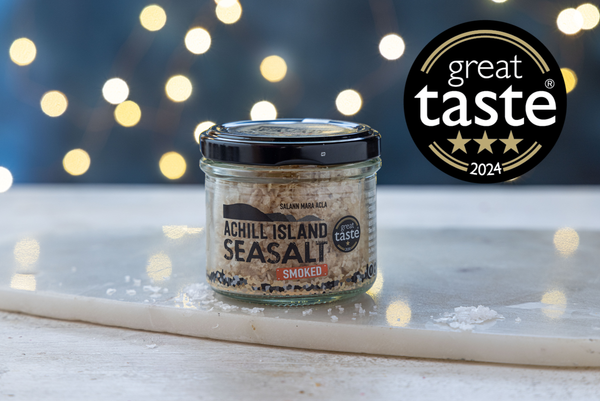 Jar of Achill Island Smoked Seasalt with a 'Great Taste' award logo on a blurred lights background