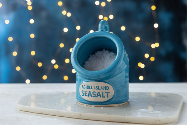 Blue Sea Salt Pig container of Achill Island Seasalt on a white surface with a blurred light background