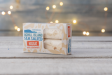 Box of Achill Island Sea Salted Nougat with cashew nuts on a wooden surface with blurred lights in the background.