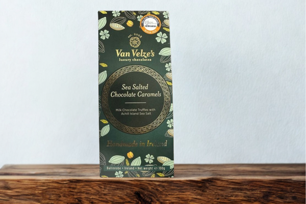 Van Velze chocolate caramel packaging on a wooden surface with a white background