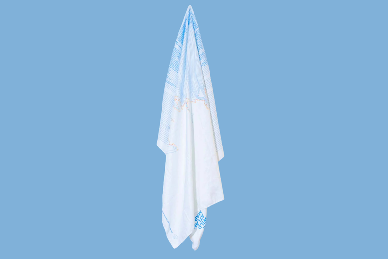 White towel with blue trim hanging against a light blue background